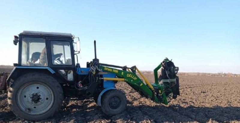 Трактор забирає залишки ворожої техніки з поля